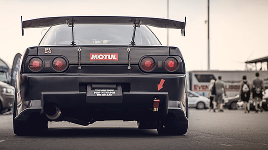 black Nissan Skyline GT-R R32 near four people walking thumbnail