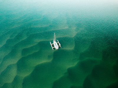 white boat on body of water in high angle shot thumbnail