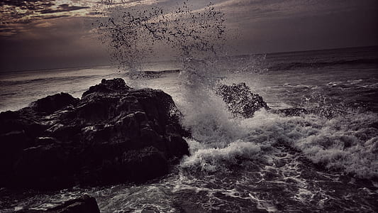 ocean wave near gray rock formation under cloudy sky at daytime thumbnail