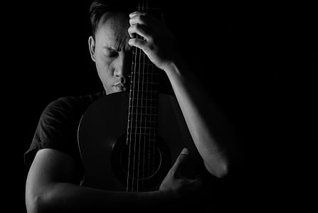 man hugging guitar grayscale photography thumbnail
