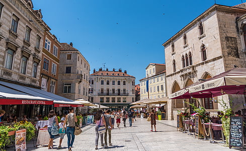 people walking on pavement surrounded by buildings thumbnail