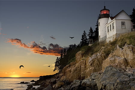 low angle view of lighthouse near body of water during golden hour thumbnail