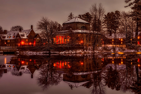 brown concrete building  with lights reflecting on water photo thumbnail