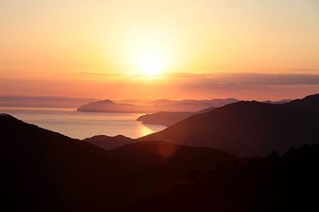 landforms along body of water during sunset thumbnail