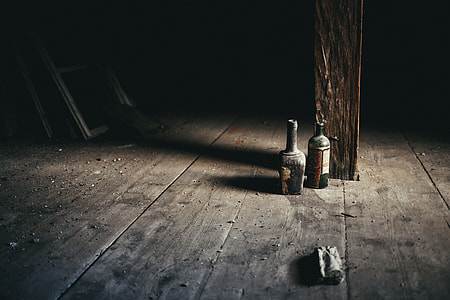 two black glass bottles near wooden post thumbnail