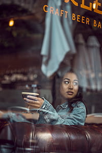 woman wearing blue denim jacket and holding clear cocktail glass thumbnail