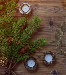 three tealight candles near branch of fir leaves with pine cones thumbnail