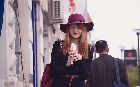 woman wearing sun hat holding ice cream near building thumbnail