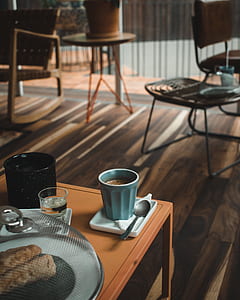 blue ceramic cup beside stainless steel spoon on brown wooden table thumbnail
