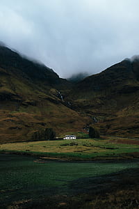 white house alone on grass field near mountain range thumbnail