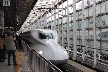 man taking photo of bullet train at daytime thumbnail
