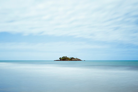 island on sea under white clouds thumbnail