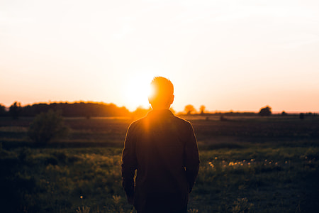person standing on green grass under dark sky during golden hour thumbnail
