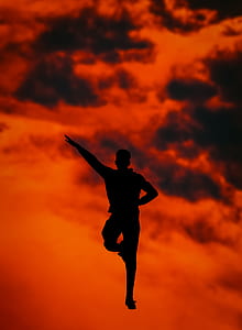 silhouette of man on mid air under black and red sky at daytime thumbnail