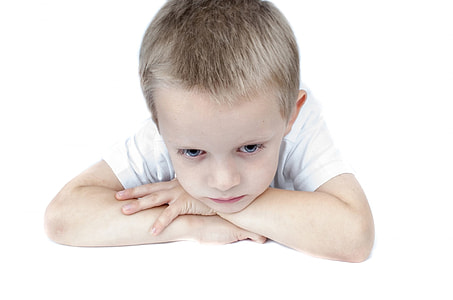boy wearing white shirt arms and head on table thumbnail