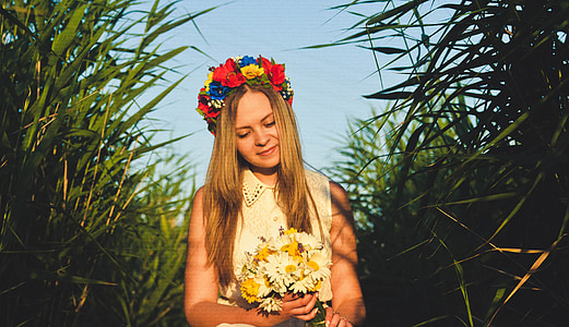 woman holding bouquet of flowers standing in between grass during daytime thumbnail