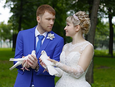 woman and woman facing each other while holding white doves thumbnail