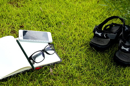 pair of black hook-and-loop sandals on grasses near white smartphone and black framed eyeglasses thumbnail