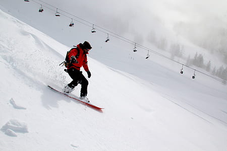 man wearing black and red suit doing snowboarding during daytime thumbnail