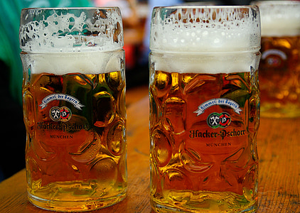 two beer filled clear beer glass mugs on brown wood surface thumbnail