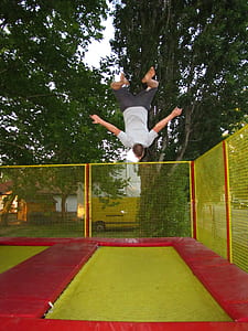 man jumping on green and red trampoline thumbnail