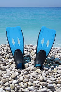 pair of flippers on stone covered shore during day thumbnail