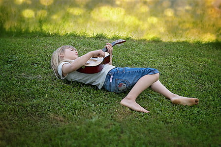girl lying on green grass while playing guitar thumbnail