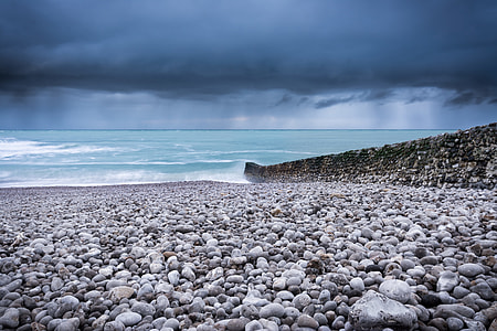 body of water near rock wall at daytime thumbnail