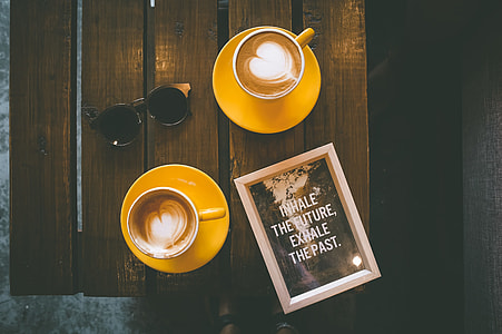 two orange coffee cup with saucer on top of wooden table thumbnail
