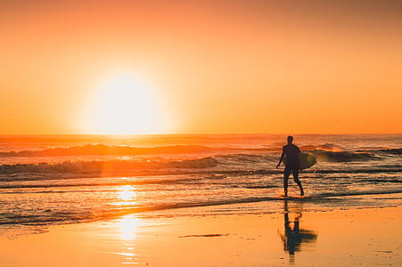 man walking on seashore during sunset thumbnail