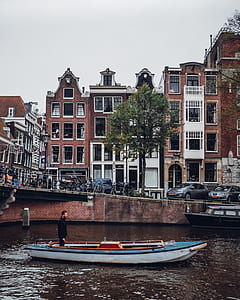 man standing on motorboat near building thumbnail