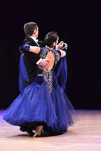 woman in blue trumpet dress dancing with man in black tuxedo thumbnail