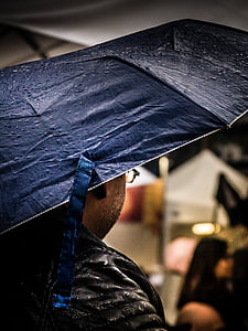 low light photography of man carrying black umbrella thumbnail