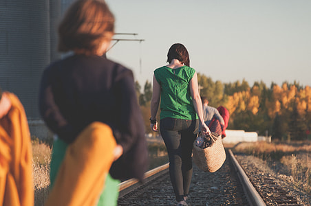woman wearing green sleeveless top walking on railway at daytime thumbnail