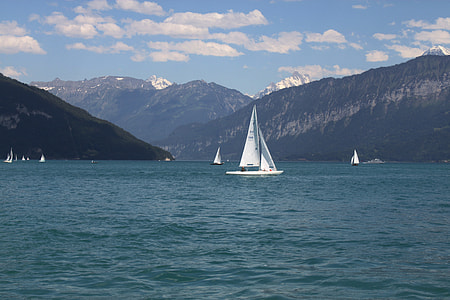 white sail boat on body of water near mountain during daytime thumbnail