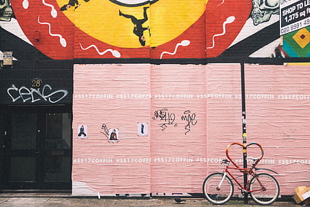 red and white bicycle beside beige painted wall thumbnail