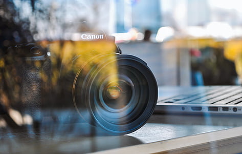 black Canon camera beside gray laptop computer on desk thumbnail