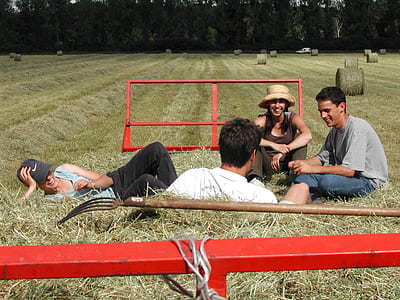 two men and two women sitting on bale of hay thumbnail