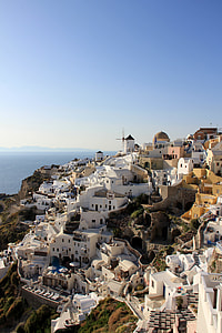white buildings on rock formation with sea in distant thumbnail