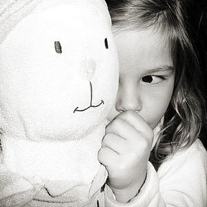 grayscale photography of a child holding her plush toy thumbnail