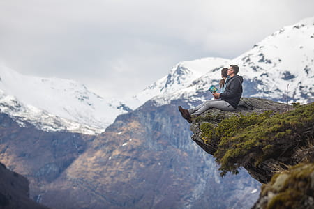 man sitting on cliff of mountain during daytime thumbnail