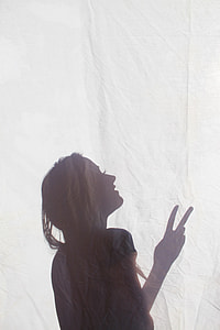 silhouette of woman doing peace sign on white textile thumbnail