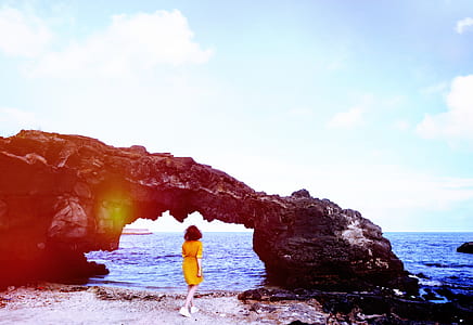 woman near gray rock formation beside ocean during daytime thumbnail
