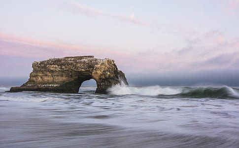 brown arch on ocean at daytime thumbnail