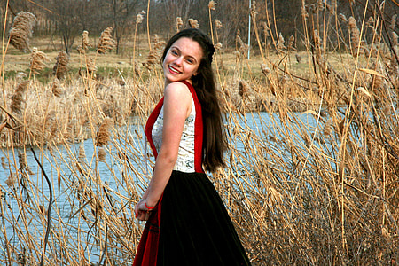 woman happily smiling standing near brown tall grasses and river thumbnail