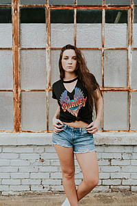 woman wearing black Journey crop-top and blue denim shorts standing near brown window photo thumbnail