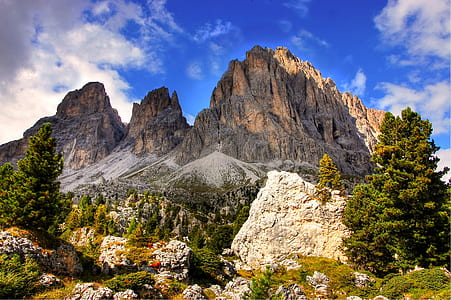 brown mountain near green trees under white clouds and blue sky at daytime thumbnail
