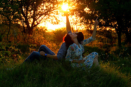 coupe leaning on each other sitting on green grasses beside trees looking at sky thumbnail
