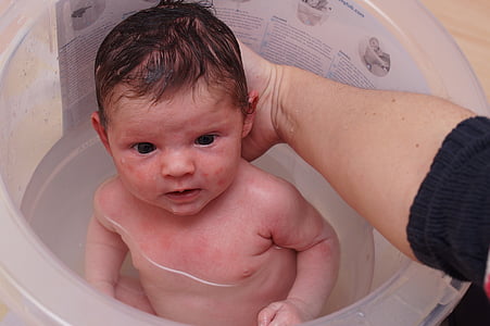 person holding baby's head for support while taking his bath thumbnail