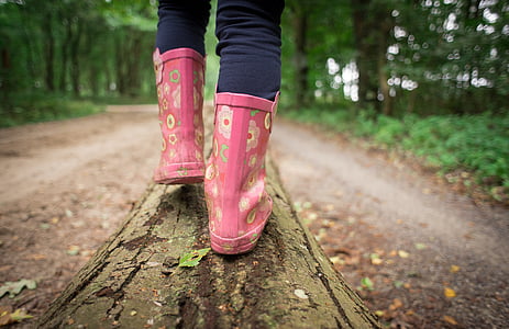 selective focus photography of person in pink floral boots walking on tree trunk thumbnail